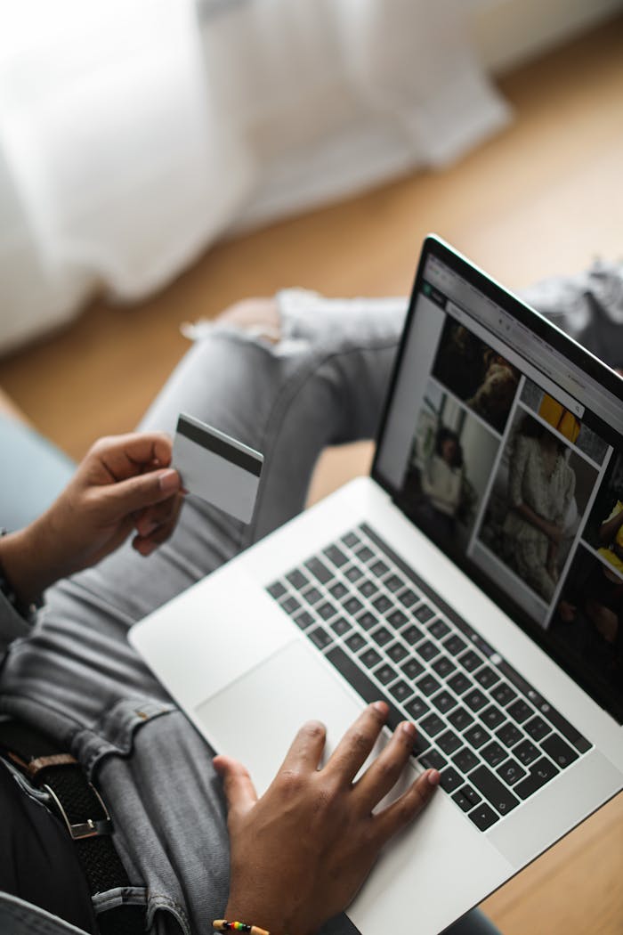 Person using credit card for online shopping on laptop in relaxed setting.